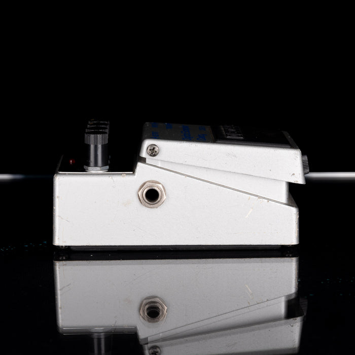 Metallic guitar effects pedal on a reflective surface with a black background