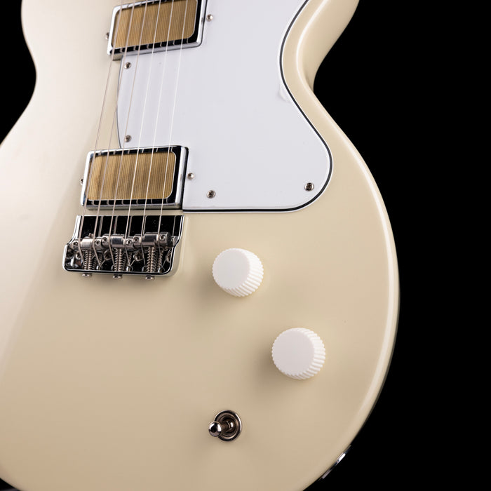 Close-up of a white electric guitar with a black background