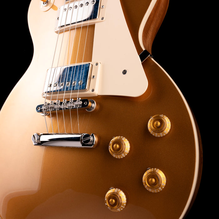 Close-up of a Les Paul electric guitar with a cream finish and gold hardware on a black background.