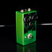 Green guitar effects pedal with black details on a reflective surface