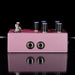 Purple guitar effects pedal with knobs and jacks on a reflective surface