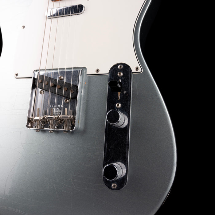 Close-up of a Fender electric guitar with a black pickguard and control knobs on a white background.