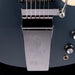 Close-up of a Gibson guitar bridge and tuning pegs on a dark background