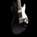 Black electric guitar with a white pickguard on a black background