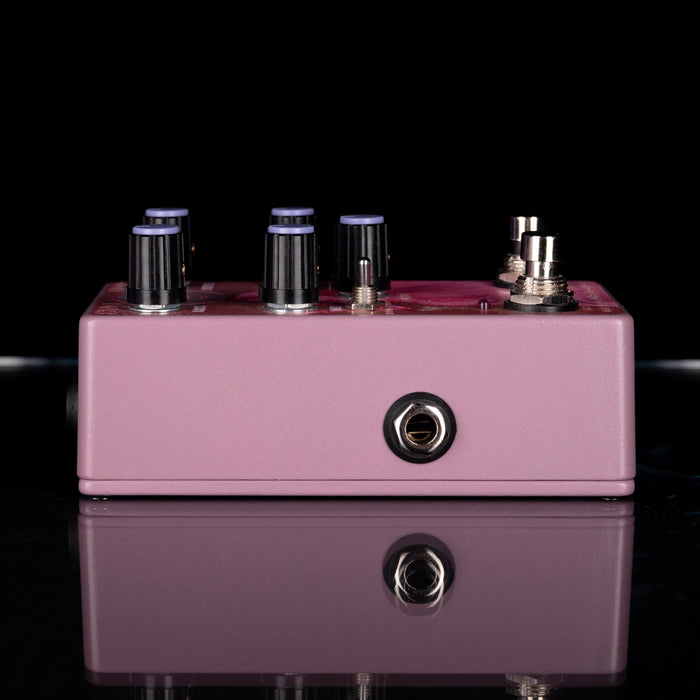 Purple guitar effects pedal with knobs and jacks on a reflective surface