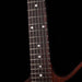 Close-up of a guitar neck with frets and strings on a black background