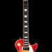 Red electric guitar with a white pickguard on a black background
