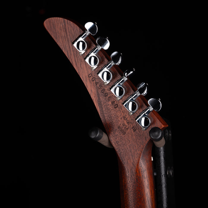 Close-up of a guitar headstock with tuning pegs on a black background