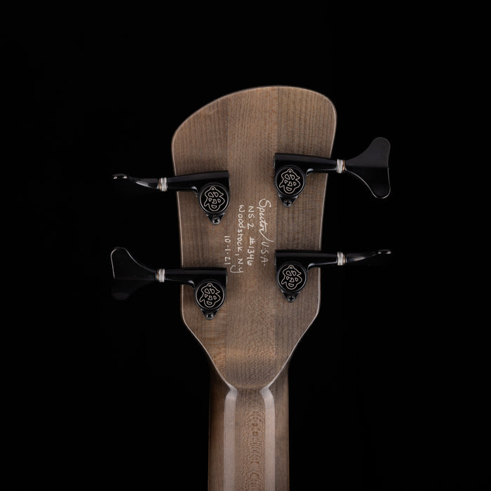 Close-up of a guitar headstock with tuning pegs on a black background