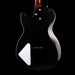 Black electric guitar with a white pickguard on a black background
