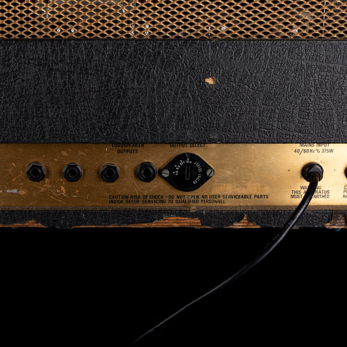 Close-up of a guitar amplifier with control knobs and labels.