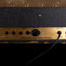 Close-up of a guitar amplifier with control knobs and labels.