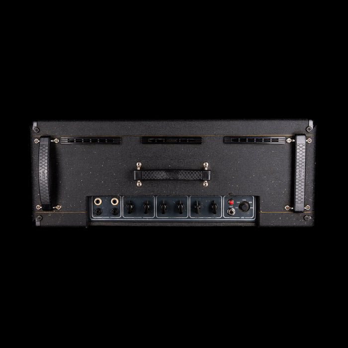 Back panel of a guitar amplifier with control knobs and ports on a black background