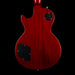 Red electric guitar body with black pickguard on a black background